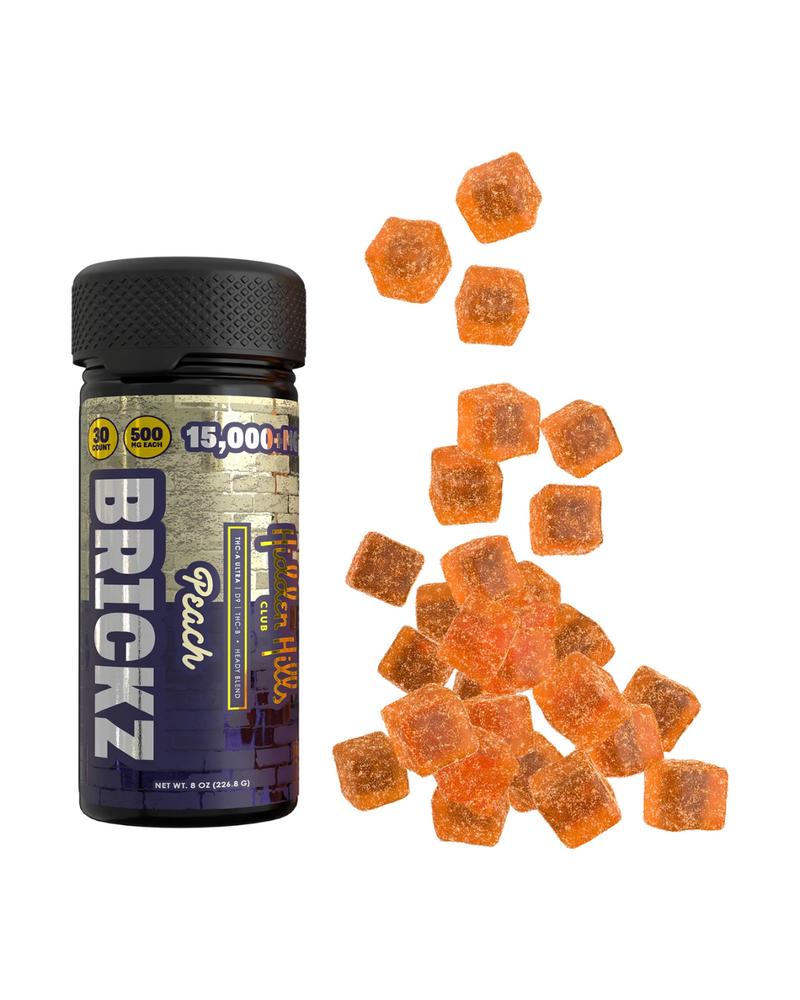 A bottle labeled "Hidden Hills Heady Blend Brickz Gummies | 15000mg" next to a group of small, orange, hexagonal gummies infused with Delta 9 live resin. The bottle indicates it contains 15,000 mg with 500 mg per piece.