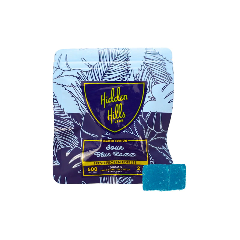 A blue edible gummy is placed next to a blue and white packet labeled "Hidden Hills - Hidden Hills Heady Blend Gummies | 2ct - Limited Edition - Fresh Frozen Edibles - 1000mg - 500mg CBD / 500mg THC," showcasing the high-quality cannabis extracts in these Heady Blend Gummies.